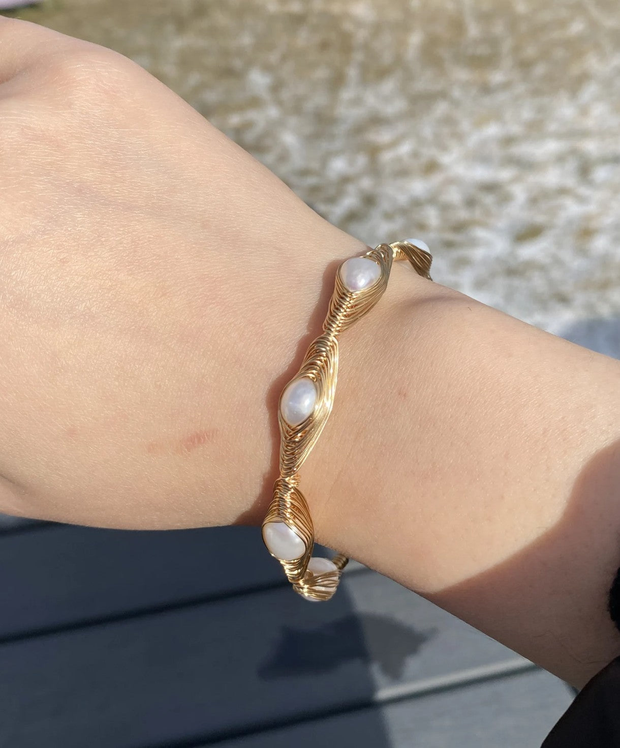 Woman wearing elegant handwired Baroque freshwater pearl open bangle cuff bracelet, showing adjustable fit in Pakistan