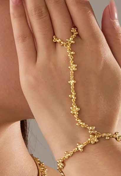 Woman wearing Bohemian golden petal hand chain bracelet, showing elegant wrist and finger accessory style in Pakistan