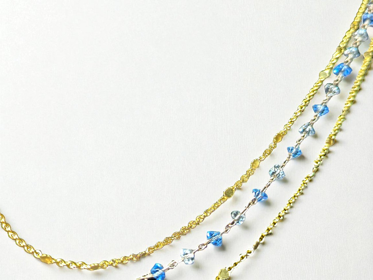Close up of sparkling golden sequins, crystal stones, and natural gravel beads on three layer necklace