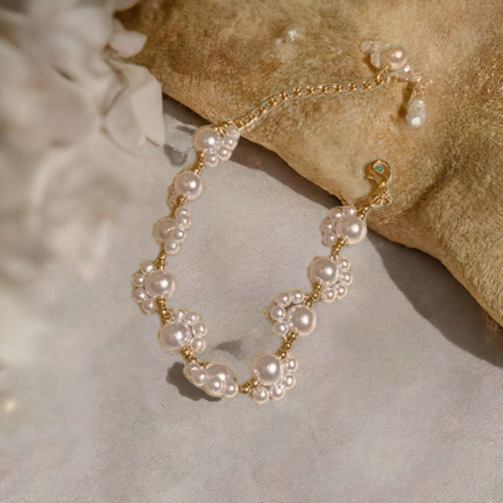 Close up of imitation pearl beads, golden-tone accents, and charming tassel on minimalist bracelet