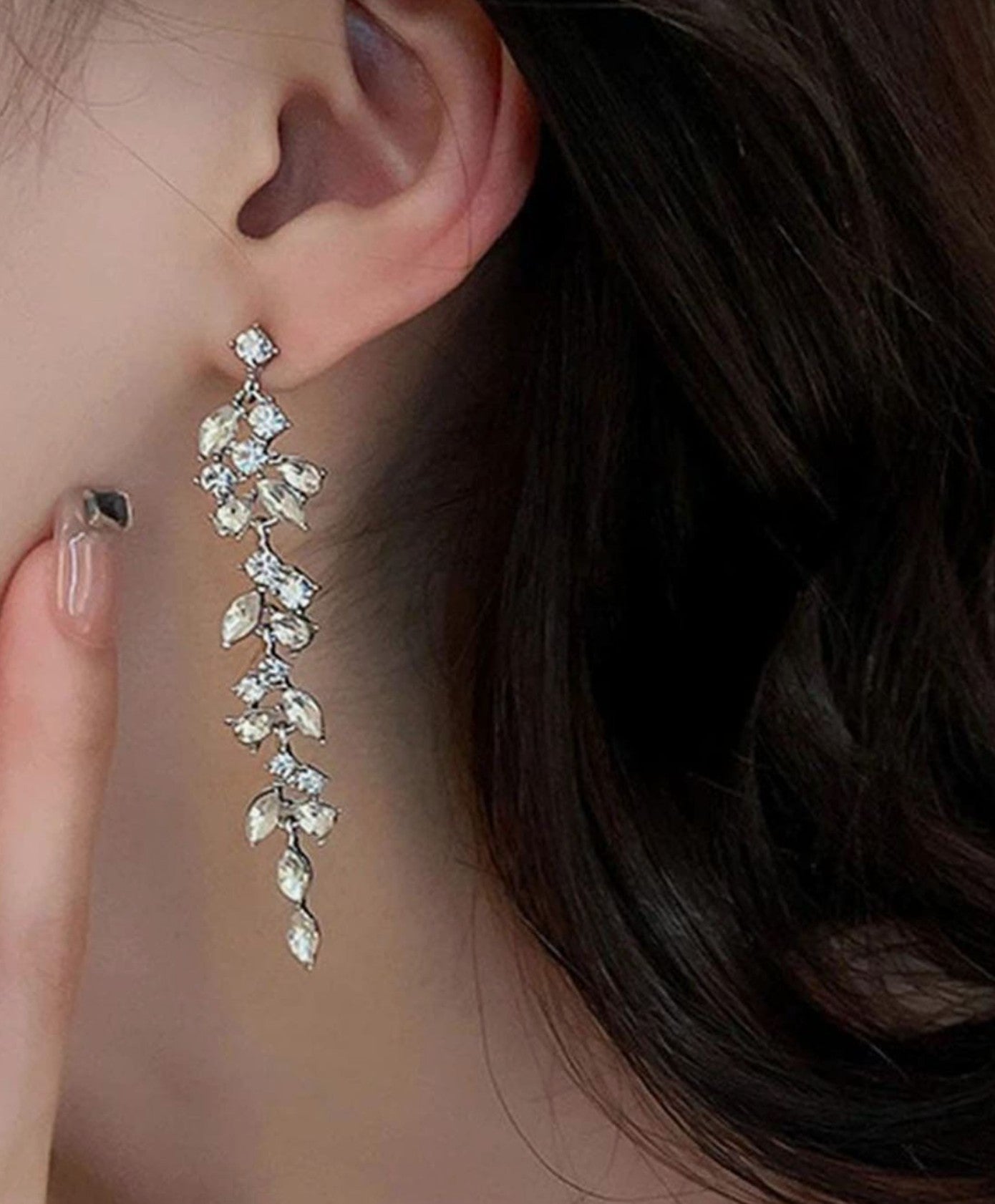 Woman wearing sparkling crystal rhinestone leaf shaped ear hangers, showing elegant movement