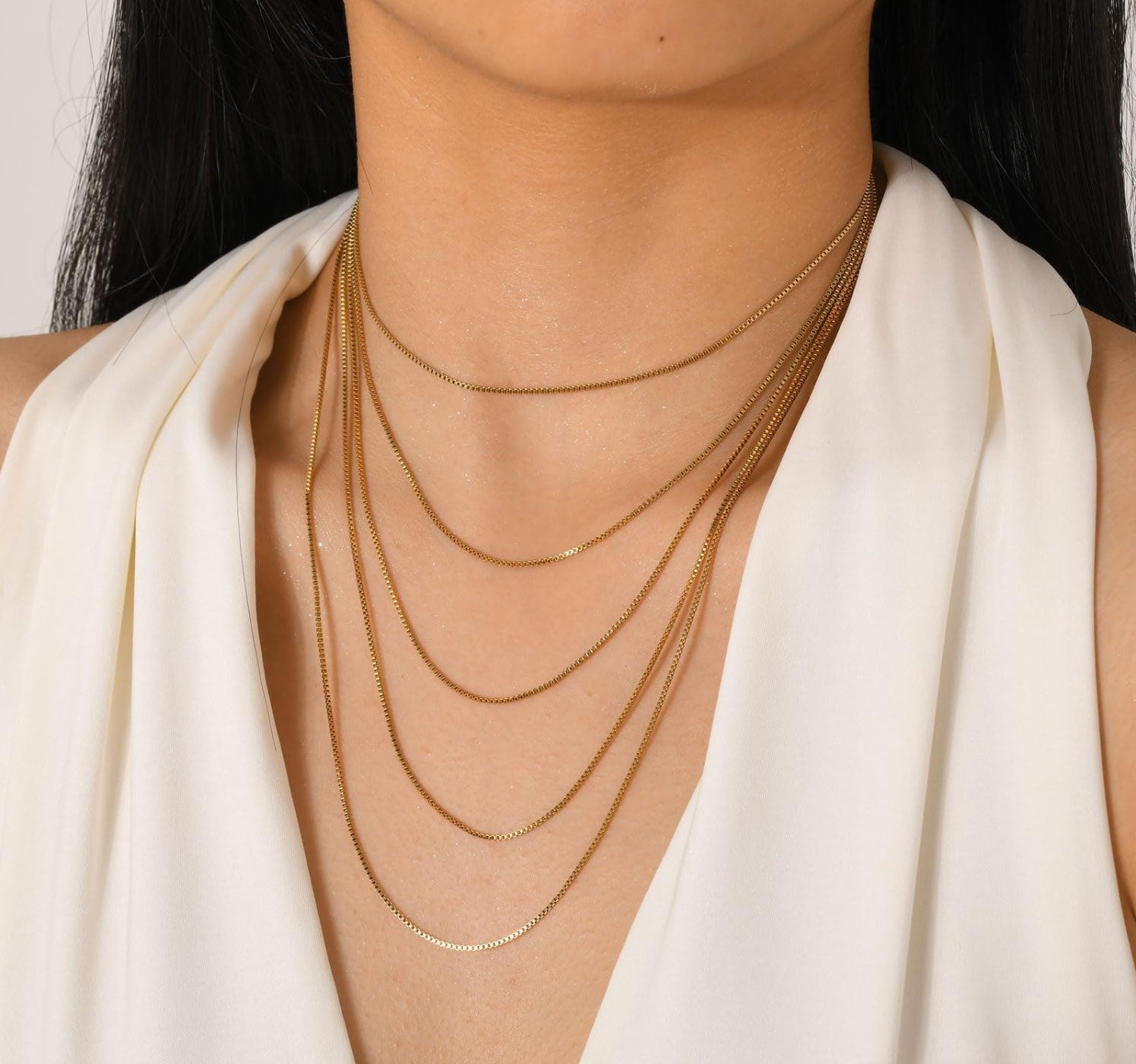 Woman wearing elegant multi layer chain necklace, showing versatile layering style