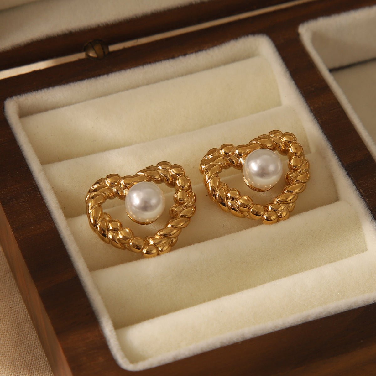 Close up of luminous pearl and intricate retro twist heart design on 18K gold plated studs