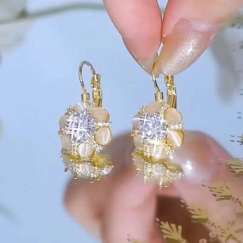 Close up of sparkling white opal earrings, showing mesmerizing play of color